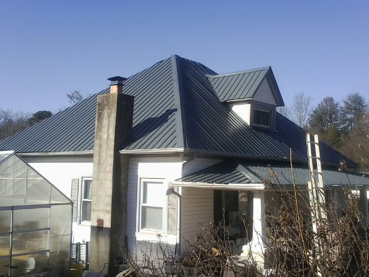 Dark blue standing seam metal roof on a white farmhouse with dormer — Slate & Tile Roof Repair by Roofing Brothers in Plumerville