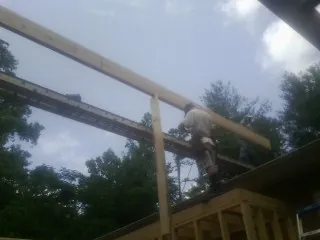 Carpenter setting a ridge beam over a new addition frame — Ice Dam Removal by Roofing Brothers in Plumerville