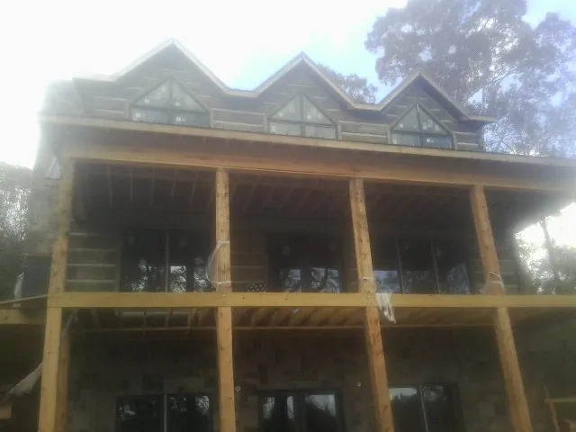 Dormers and porch framing on a large log home under construction — Roof Coating work by our crew in Plumerville