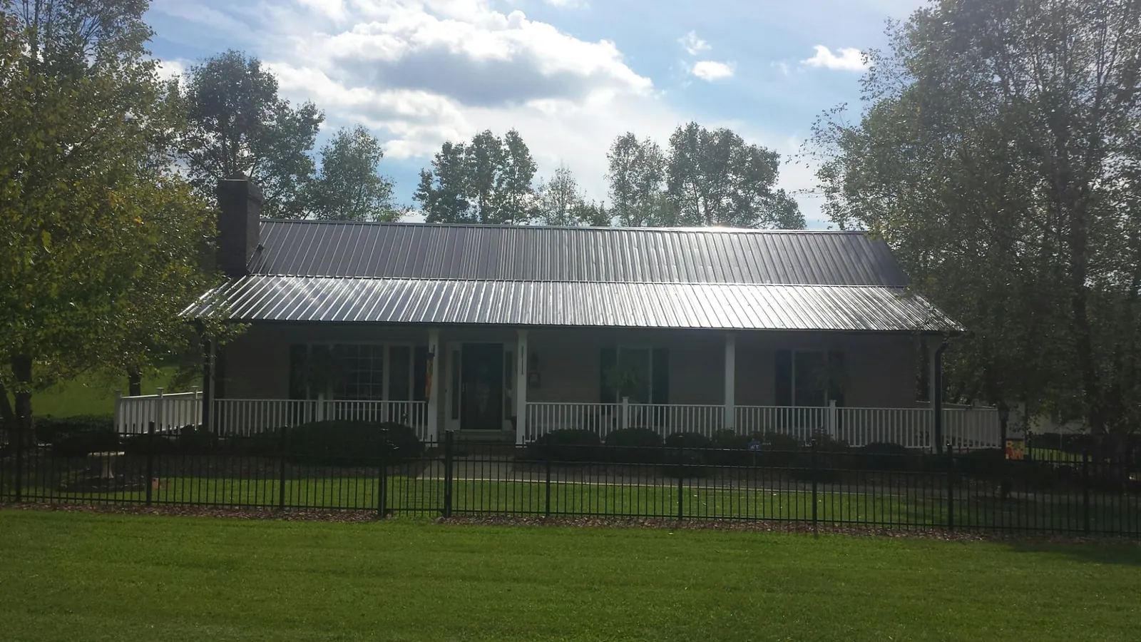 Gray metal roof on a brick ranch with a full width front porch — Gutter Guard Installation work by our crew in Plumerville