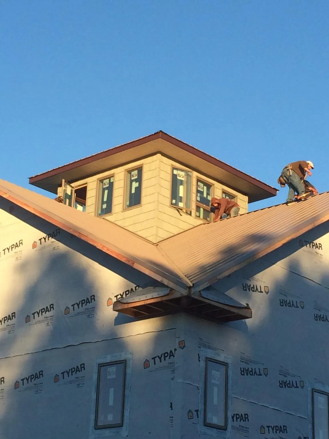 Roofers working around a rooftop cupola on a new metal roof at sunset — Roof Waterproofing in Plumerville by Roofing Brothers